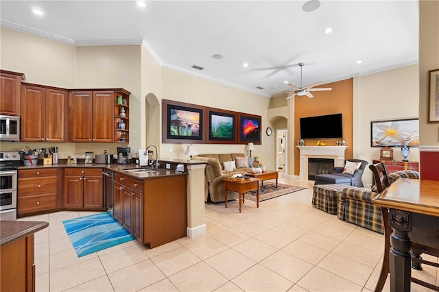 kitchen featuring light tile patterned floors, ornamental molding, a sink, appliances with stainless steel finishes, and dark countertops