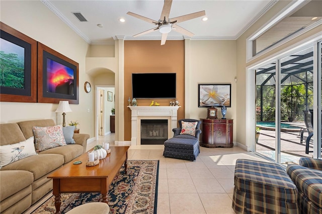 living area featuring visible vents, light tile patterned flooring, a fireplace, crown molding, and ceiling fan