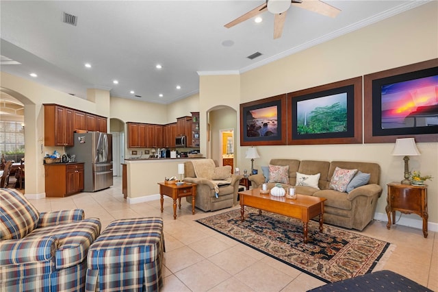 living area featuring light tile patterned floors, visible vents, baseboards, arched walkways, and crown molding