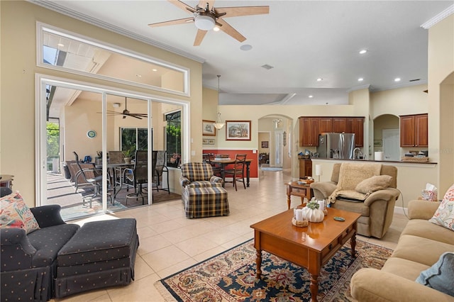 living area featuring visible vents, a ceiling fan, arched walkways, light tile patterned flooring, and crown molding