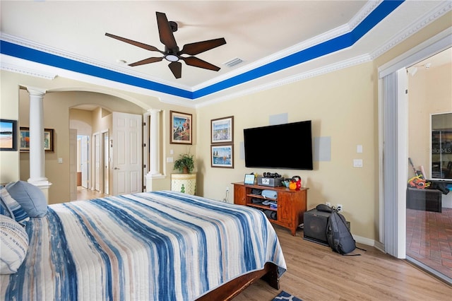 bedroom featuring visible vents, light wood-type flooring, and decorative columns