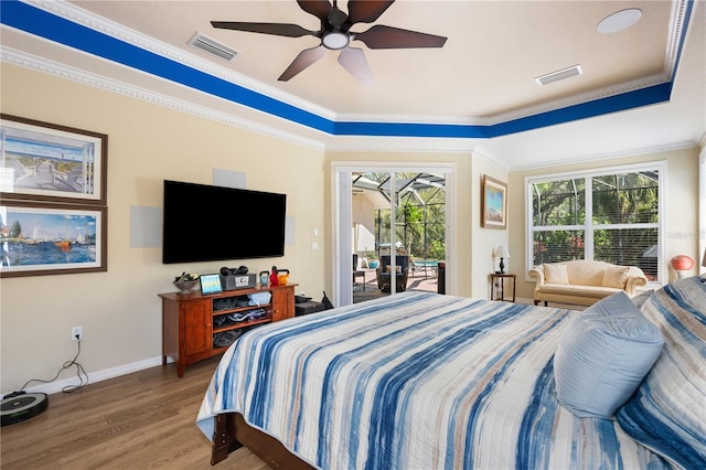 bedroom with visible vents, ornamental molding, a tray ceiling, wood finished floors, and access to exterior