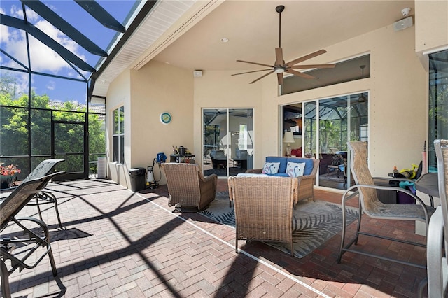 view of patio featuring glass enclosure, an outdoor hangout area, and ceiling fan