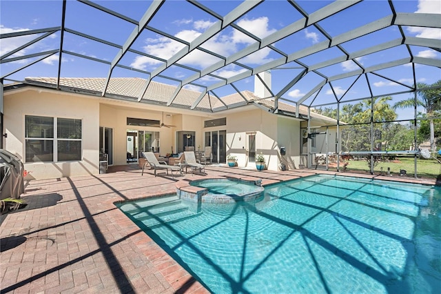 view of swimming pool featuring a patio area, glass enclosure, a pool with connected hot tub, and ceiling fan