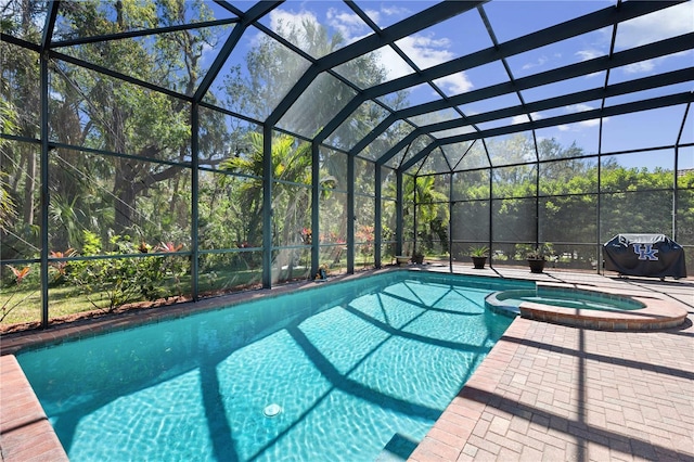 view of swimming pool with glass enclosure, a patio, a pool with connected hot tub, and a grill