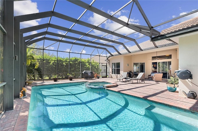 view of swimming pool featuring glass enclosure, a pool with connected hot tub, a ceiling fan, and a patio area