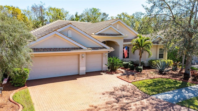 view of front of home featuring a tile roof, decorative driveway, an attached garage, and stucco siding