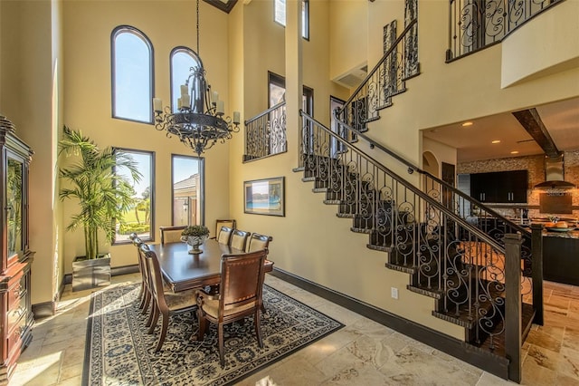 dining room featuring stairs, an inviting chandelier, a high ceiling, and baseboards