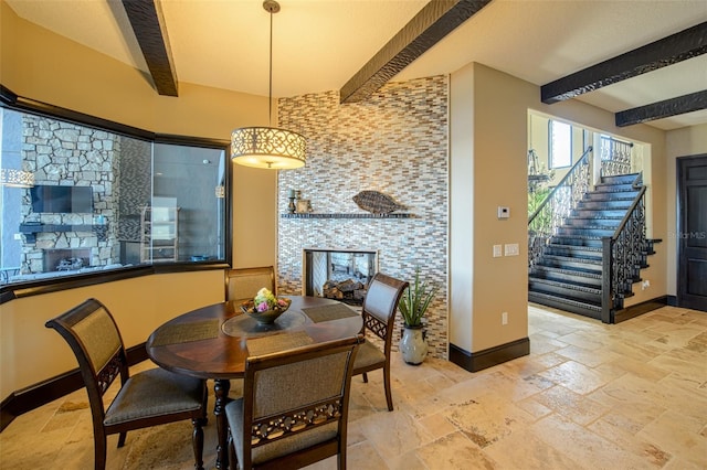 dining area featuring stone tile floors, stairway, beam ceiling, and baseboards