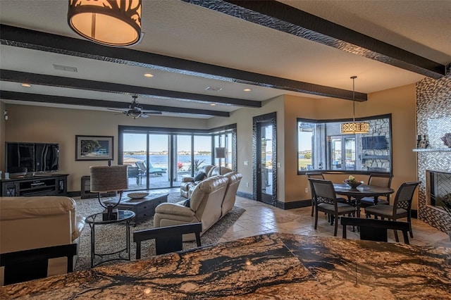 living area featuring visible vents, baseboards, beam ceiling, a fireplace, and a textured ceiling