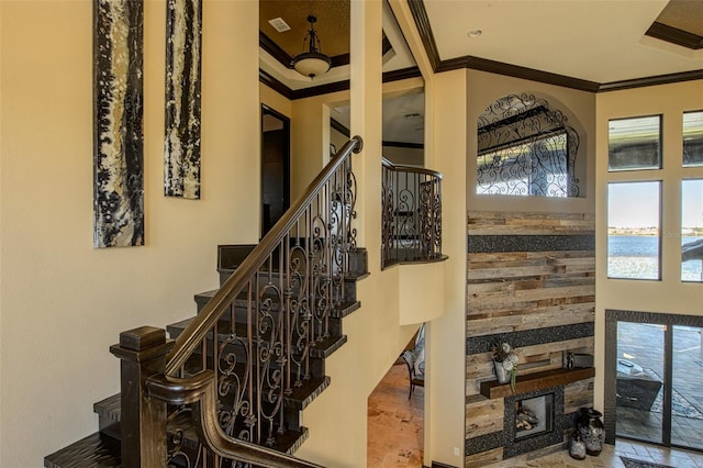 stairway featuring a fireplace, a water view, and ornamental molding