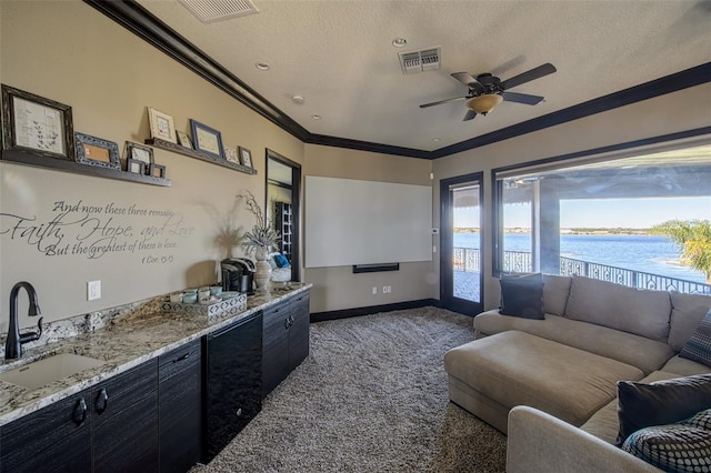 living room featuring visible vents, a water view, ornamental molding, carpet floors, and a textured ceiling