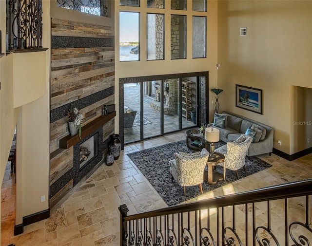 living area featuring visible vents, baseboards, stone tile floors, a fireplace, and a towering ceiling