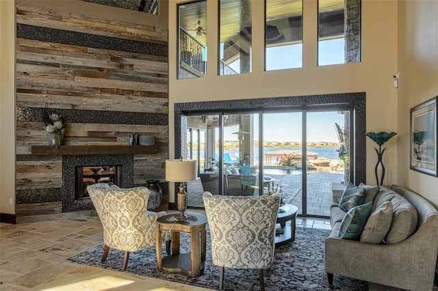 living area with a high ceiling, a multi sided fireplace, and stone tile flooring