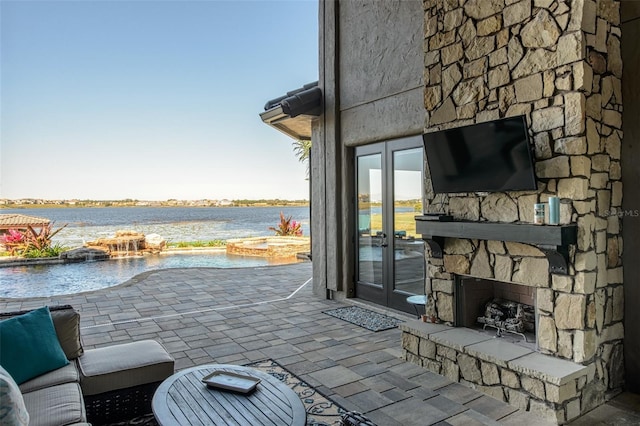 view of patio featuring an in ground hot tub and an outdoor stone fireplace