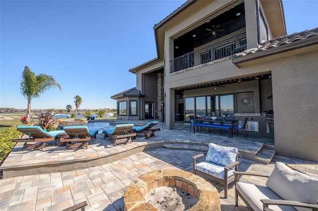 view of patio featuring outdoor dining area, a balcony, an outdoor living space with a fire pit, and a ceiling fan