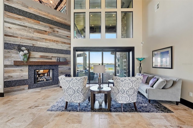 living area with stone tile flooring, a towering ceiling, a multi sided fireplace, and visible vents