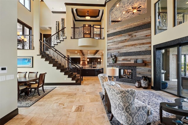 living room featuring stone tile floors, baseboards, a high ceiling, and stairway