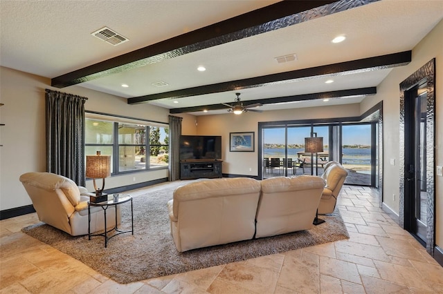 living room with stone tile flooring, visible vents, and baseboards