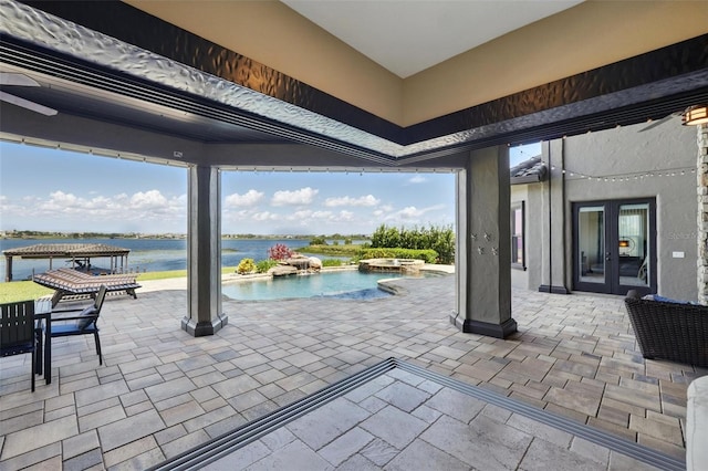 view of patio / terrace with french doors, a pool with connected hot tub, and a water view