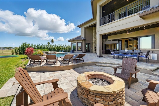 view of patio featuring an outdoor pool, a balcony, ceiling fan, outdoor dining area, and a fire pit