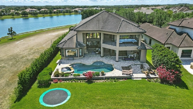 back of house featuring a lawn, a tiled roof, a water view, and a balcony