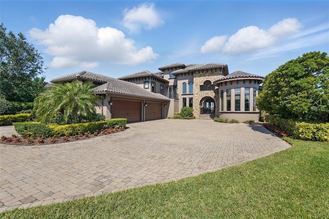 mediterranean / spanish home featuring stucco siding, an attached garage, driveway, and a tile roof