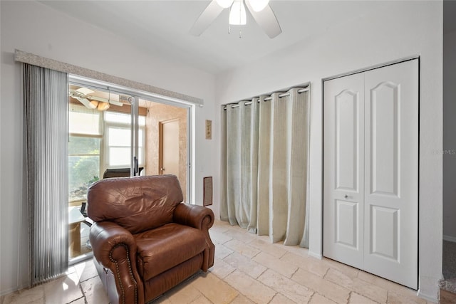 living area featuring stone tile flooring and a ceiling fan