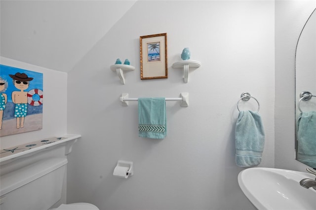 bathroom featuring toilet, a sink, and lofted ceiling