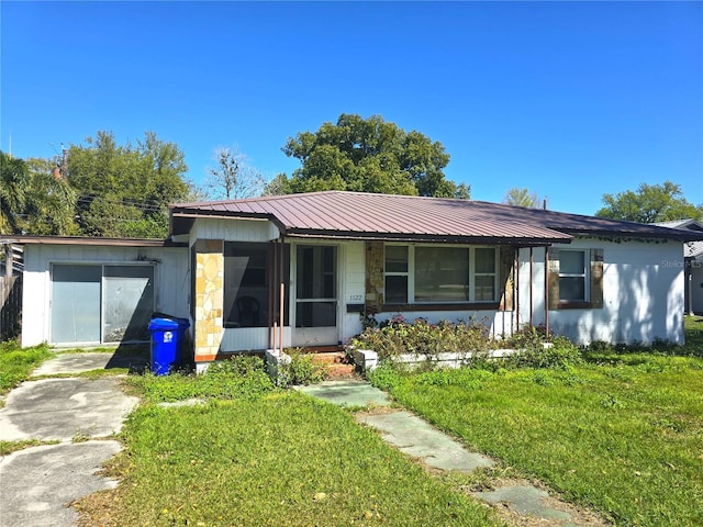 ranch-style home with metal roof, a front lawn, and driveway