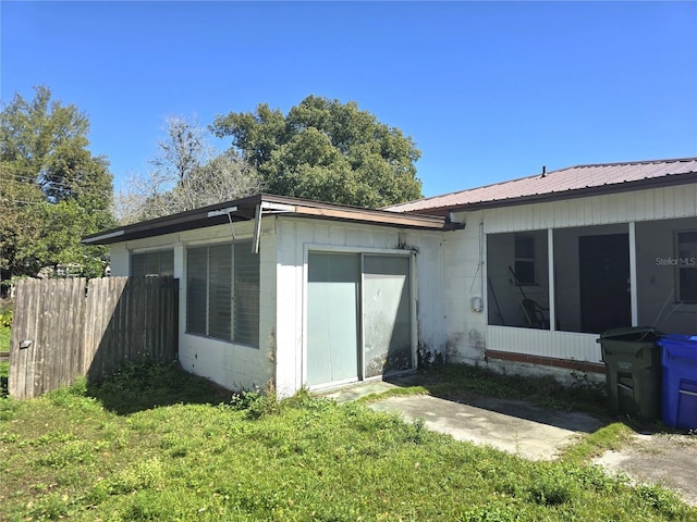 exterior space with metal roof, a yard, fence, and a sunroom