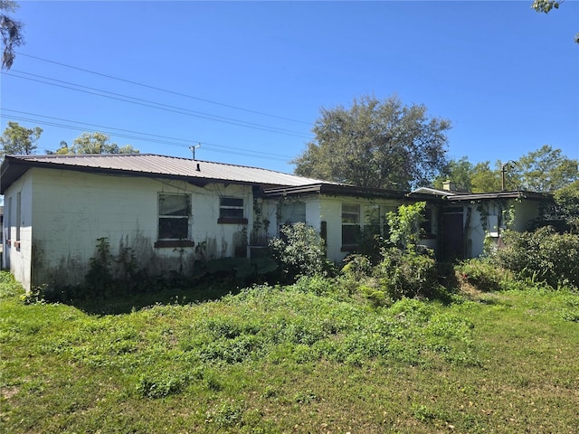 rear view of property featuring a yard and metal roof