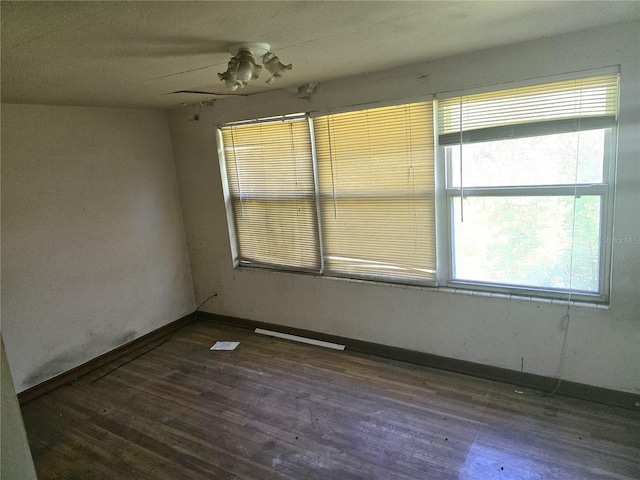 spare room with baseboards and wood finished floors