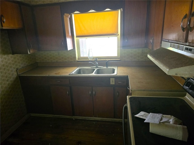 kitchen featuring wallpapered walls, electric stove, light countertops, and a sink