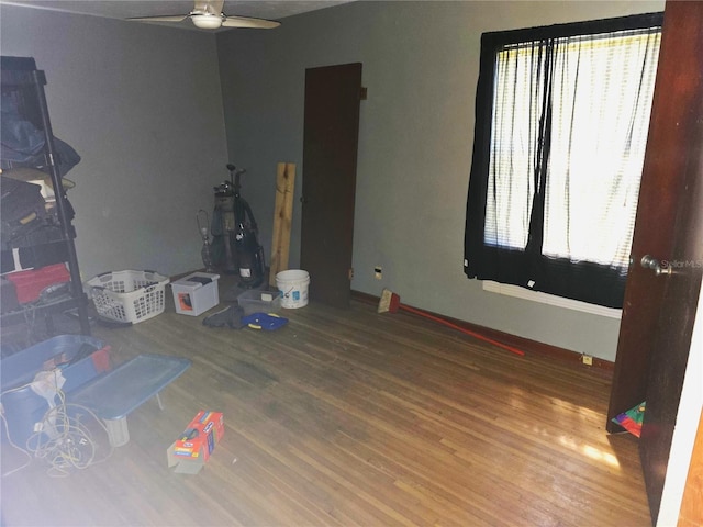 bedroom with multiple windows, baseboards, and wood finished floors