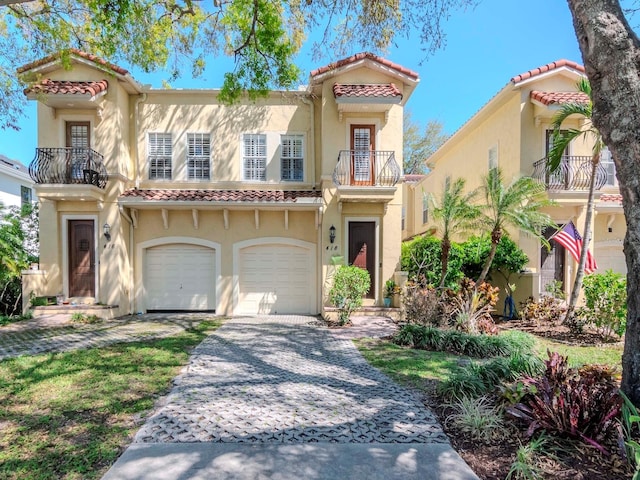 mediterranean / spanish home with stucco siding, a tile roof, decorative driveway, a garage, and a balcony