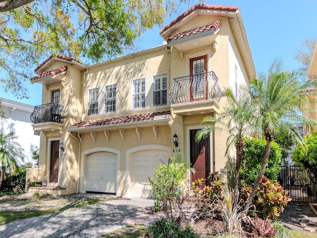 mediterranean / spanish-style house with a tiled roof, stucco siding, an attached garage, and fence