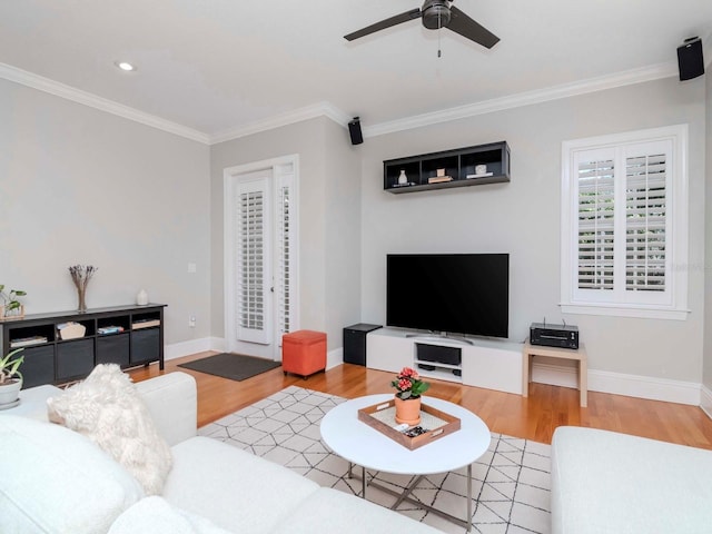 living area with baseboards, a ceiling fan, wood finished floors, and crown molding