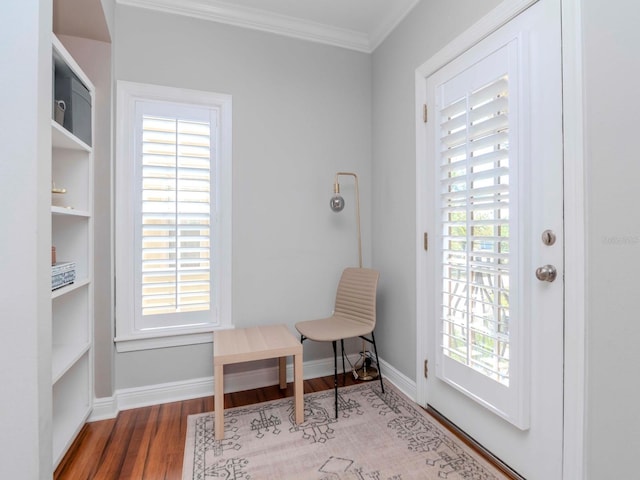 sitting room featuring wood finished floors, baseboards, a wealth of natural light, and ornamental molding