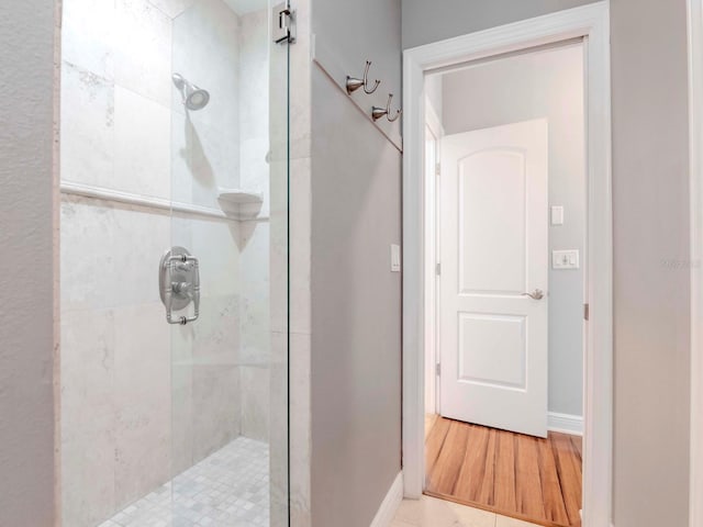 full bathroom featuring a shower stall, wood finished floors, and baseboards