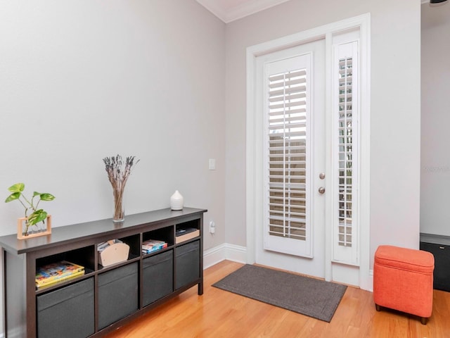 doorway with baseboards, wood finished floors, and crown molding