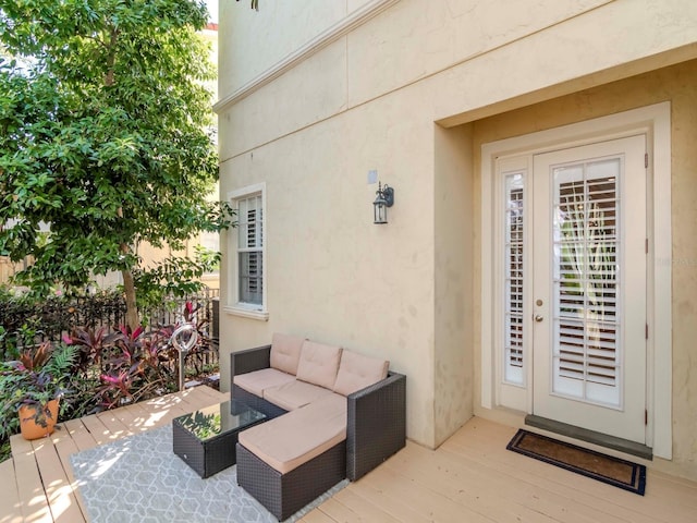 doorway to property with a wooden deck, outdoor lounge area, and stucco siding