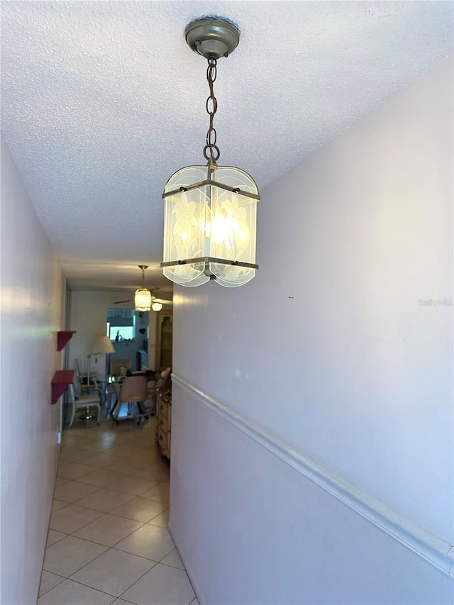 hallway featuring a chandelier, a textured ceiling, and light tile patterned floors