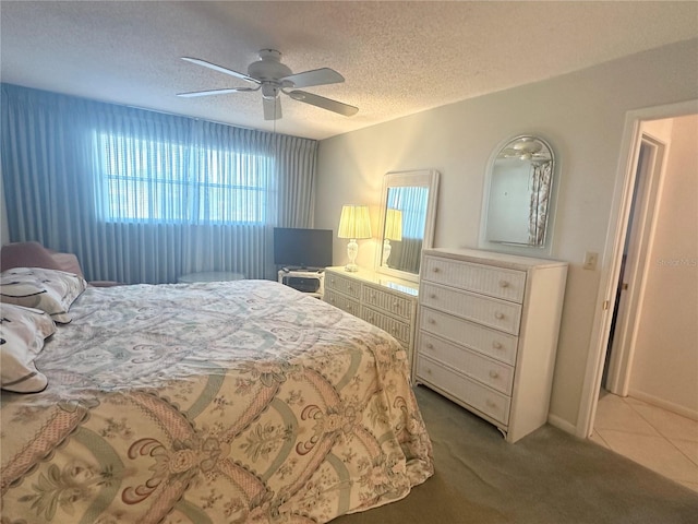 bedroom featuring light carpet, ceiling fan, and a textured ceiling