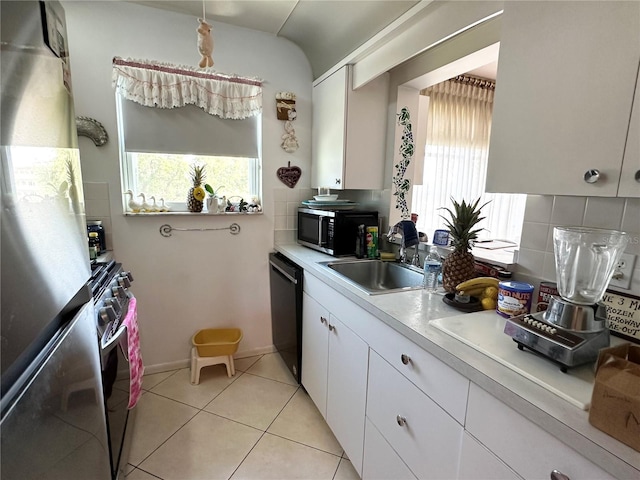 kitchen with appliances with stainless steel finishes, a healthy amount of sunlight, a sink, and decorative backsplash