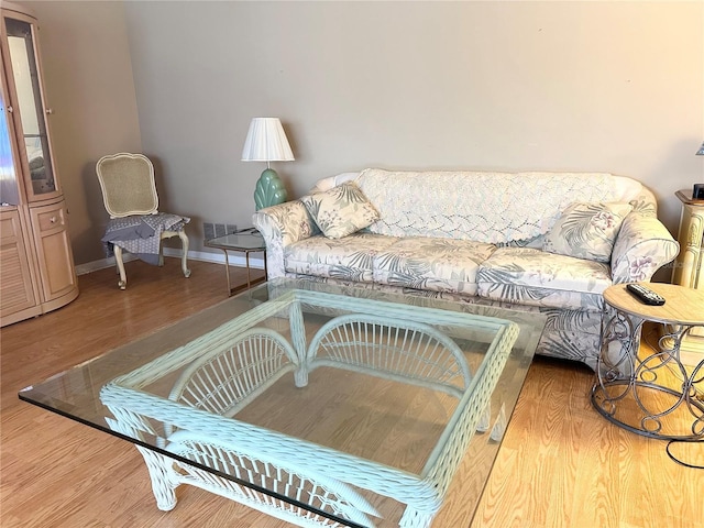 living room featuring visible vents, baseboards, and wood finished floors