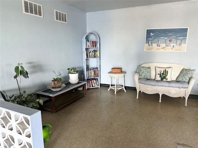 living area with visible vents, baseboards, and speckled floor