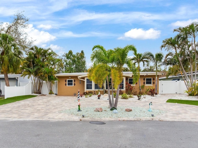 ranch-style home featuring decorative driveway, fence, and a gate