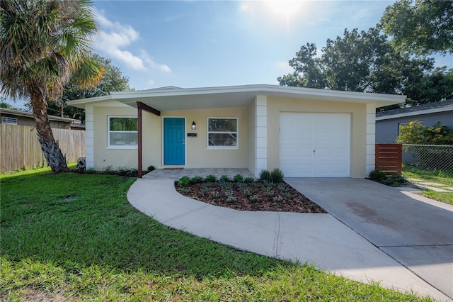 ranch-style house featuring stucco siding, concrete driveway, a front yard, fence, and a garage