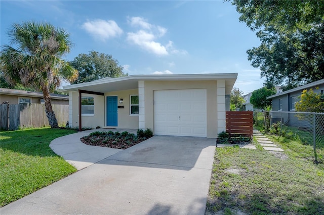 mid-century modern home with an attached garage, fence, driveway, stucco siding, and a front lawn